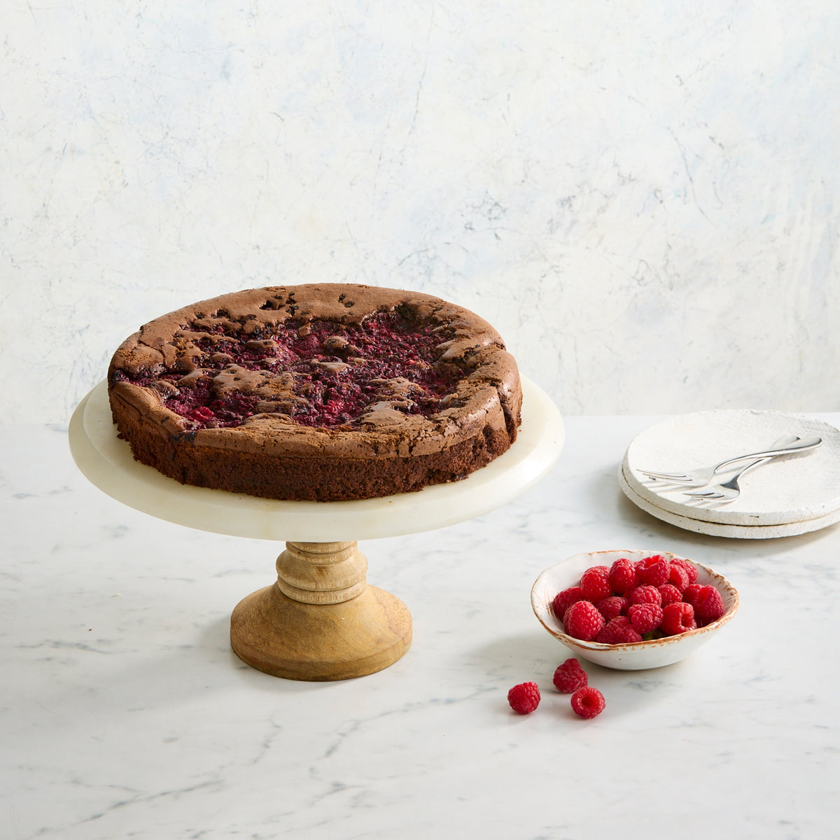 Dark chocolate and raspberry indulgence cake on stand, rich flourless chocolate cake with fresh raspberries by Bakealicious Sydney