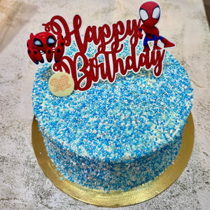 Birthday cake with blue and white sprinkles, Spider-Man-themed topper.
